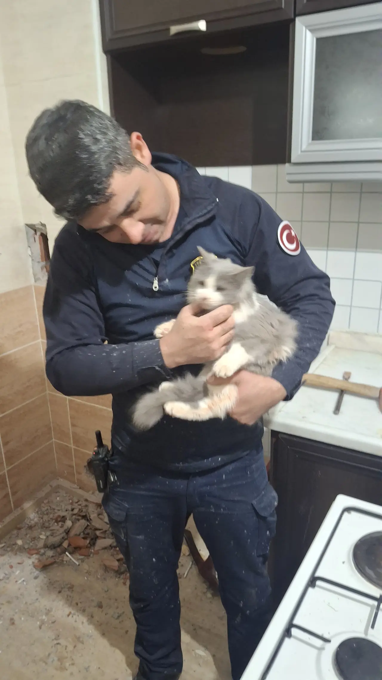 Duvarın arkasından sağ salim çıkarılan kedi ve itfaiye personeli