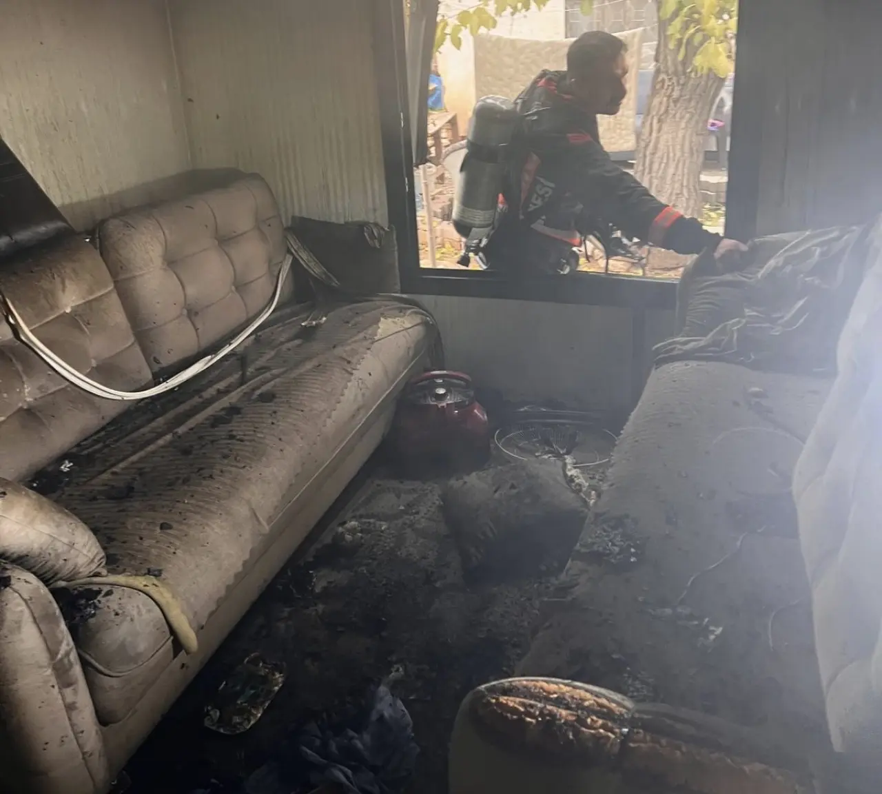 Yangın sonrası maddi hasar oluşan bahçe içerisindeki konteyner.